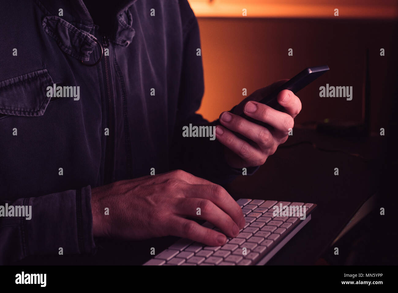 Computer Hacker mit Smartphone in den dunklen Innenraum, Low Key mit selektiven Fokus Stockfoto