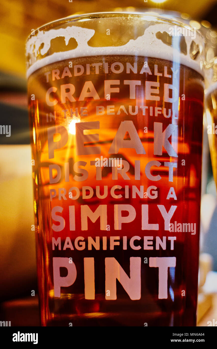 Sonnenstrahl scheint durch ein Pint Bier auf einen Tisch. Der Pub ist der Pfau Hotel in Bakewell und das Bier ist vor Ort gebraut. Stockfoto