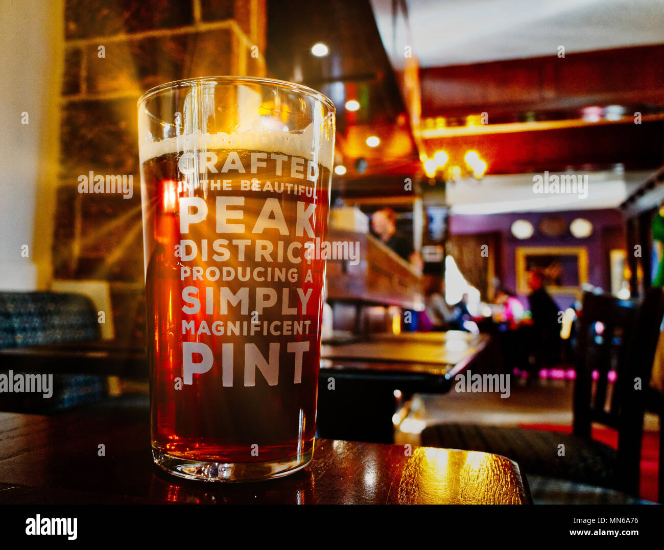 Sonnenstrahl scheint durch ein Pint Bier auf einen Tisch. Der Pub ist der Pfau Hotel in Bakewell und das Bier ist vor Ort gebraut. Stockfoto