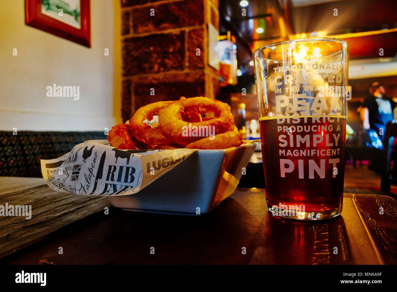 Sonnenstrahl scheint durch ein Pint Bier auf einen Tisch. Der Pub ist der Pfau Hotel in Bakewell und das Bier ist vor Ort gebraut. Stockfoto