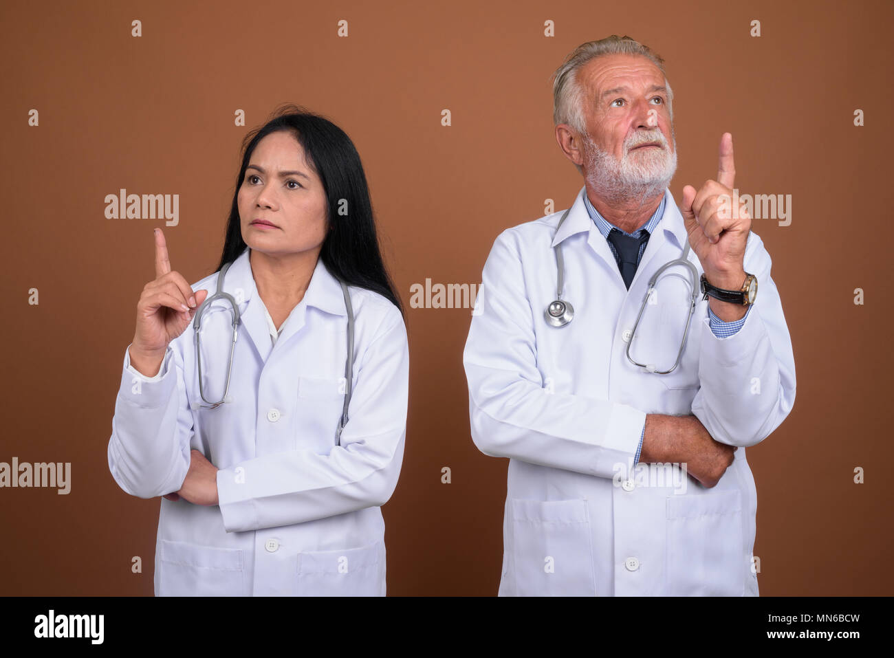 Ausgereifte multi-ethnischen paar Ärzte gegen braunen Hintergrund Stockfoto