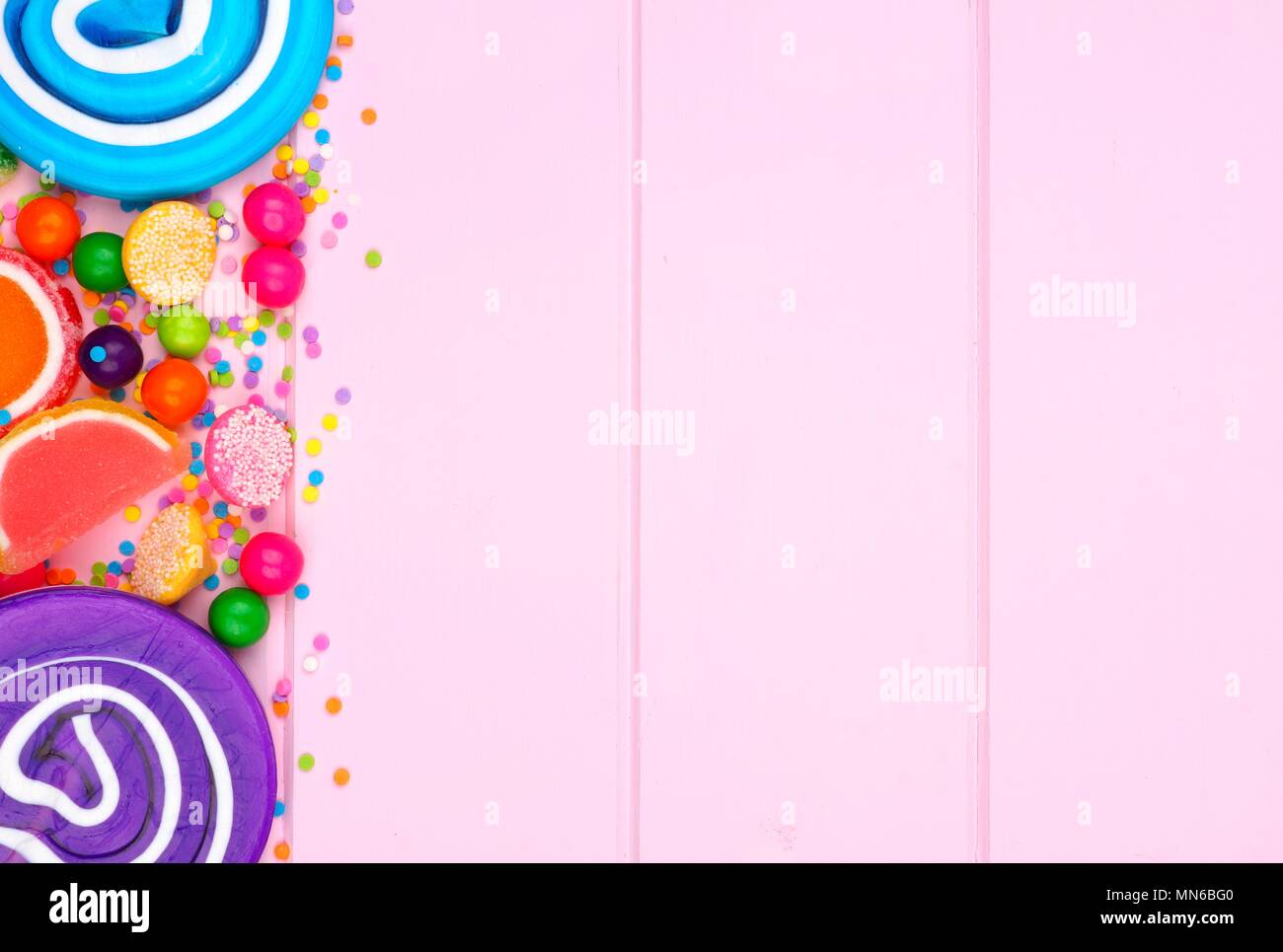 Seite Grenze der sortierten Bunte Bonbons gegen eine rosa Holz Hintergrund Stockfoto