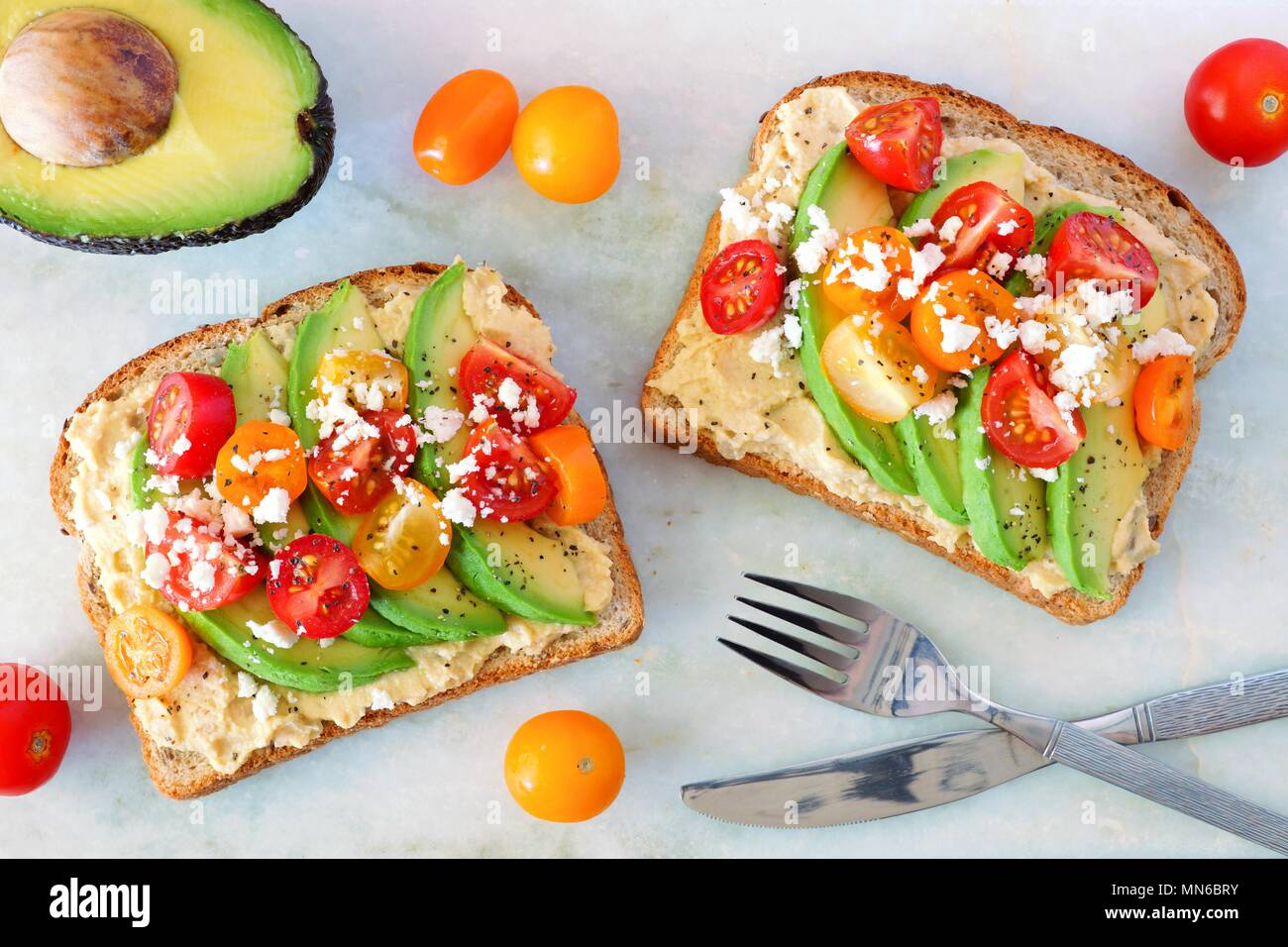 Avocado Toasts mit Hummus und Tomaten, Ansicht von oben auf weißem Hintergrund Stockfoto