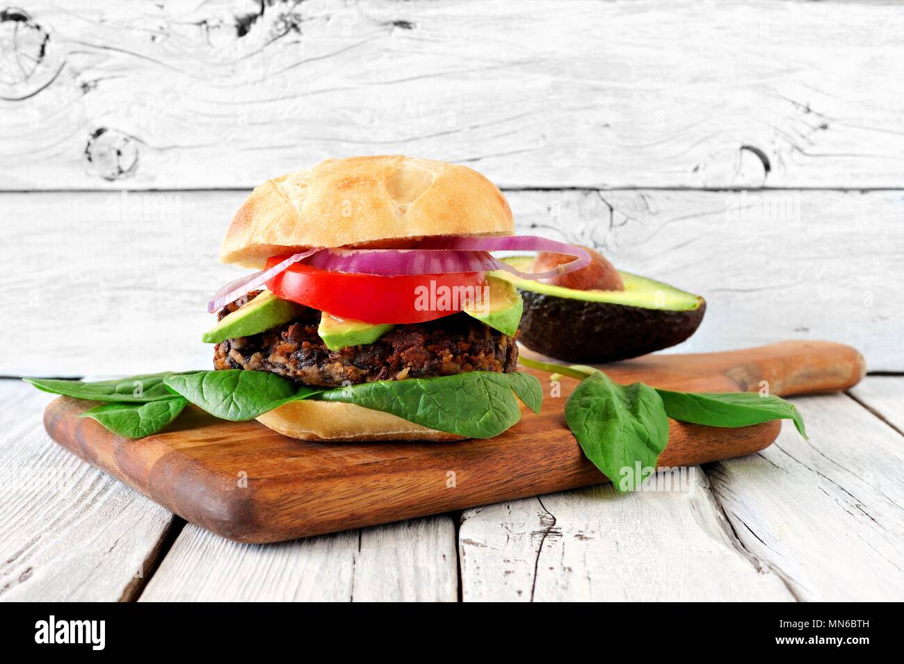 Vegetarische Bean und Süßkartoffel Burger mit Avocado und Spinat gegen eine weiße Holz Hintergrund Stockfoto