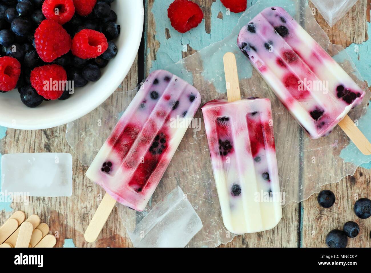 Gruppe von hausgemachten Mixed berry Joghurt Eis am Stiel auf eine rustikale Holz Hintergrund Stockfoto