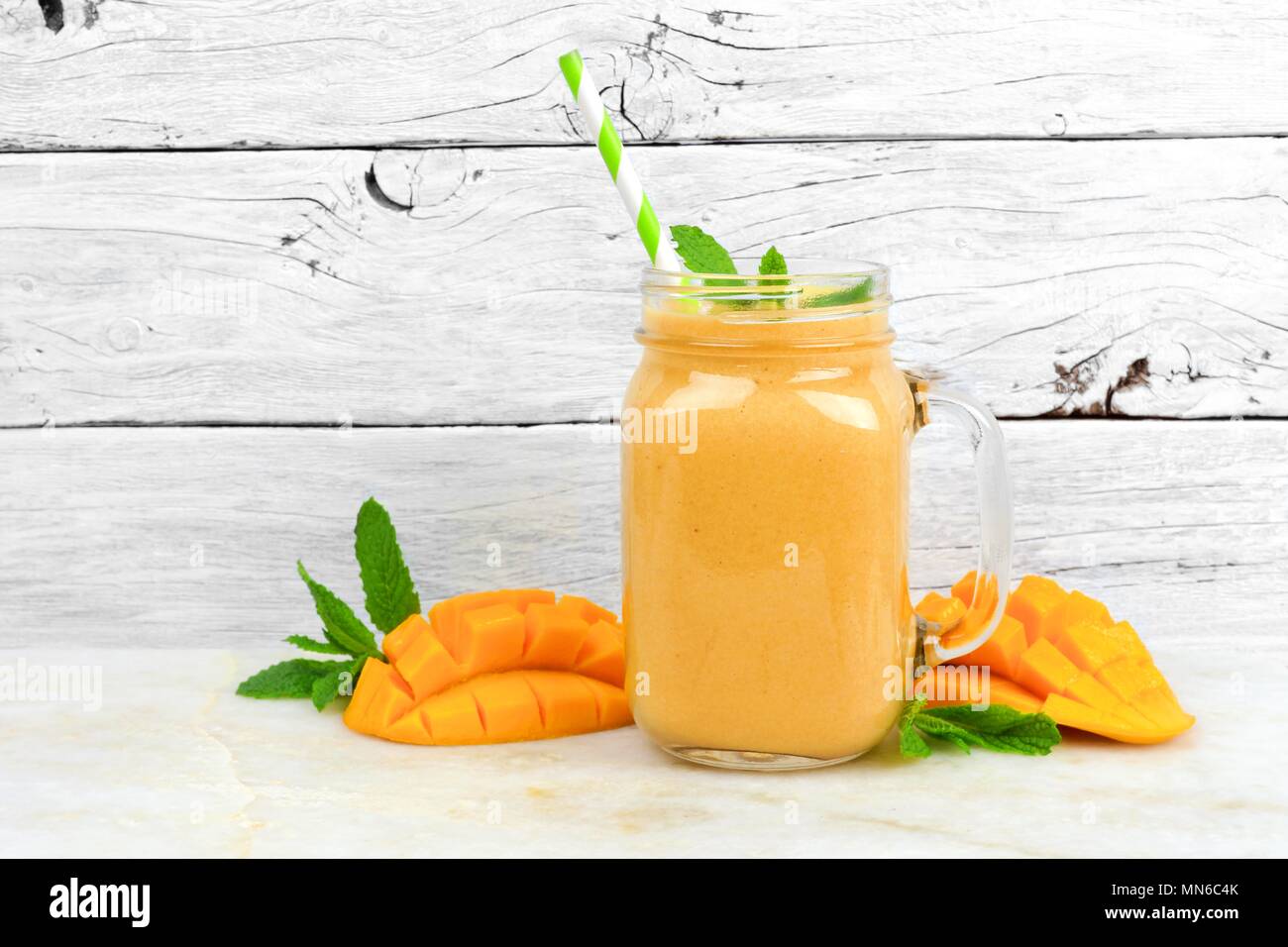 Tropische mango coconut Smoothie in einem Marmeladenglas Glas, auf einem urigen weiß Holz Hintergrund Stockfoto