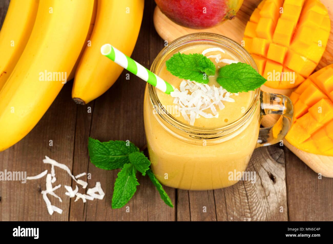 Mango, Banane, coconut Smoothie in einem Marmeladenglas Glas, Ansicht von oben auf eine rustikale Holz Hintergrund Stockfoto