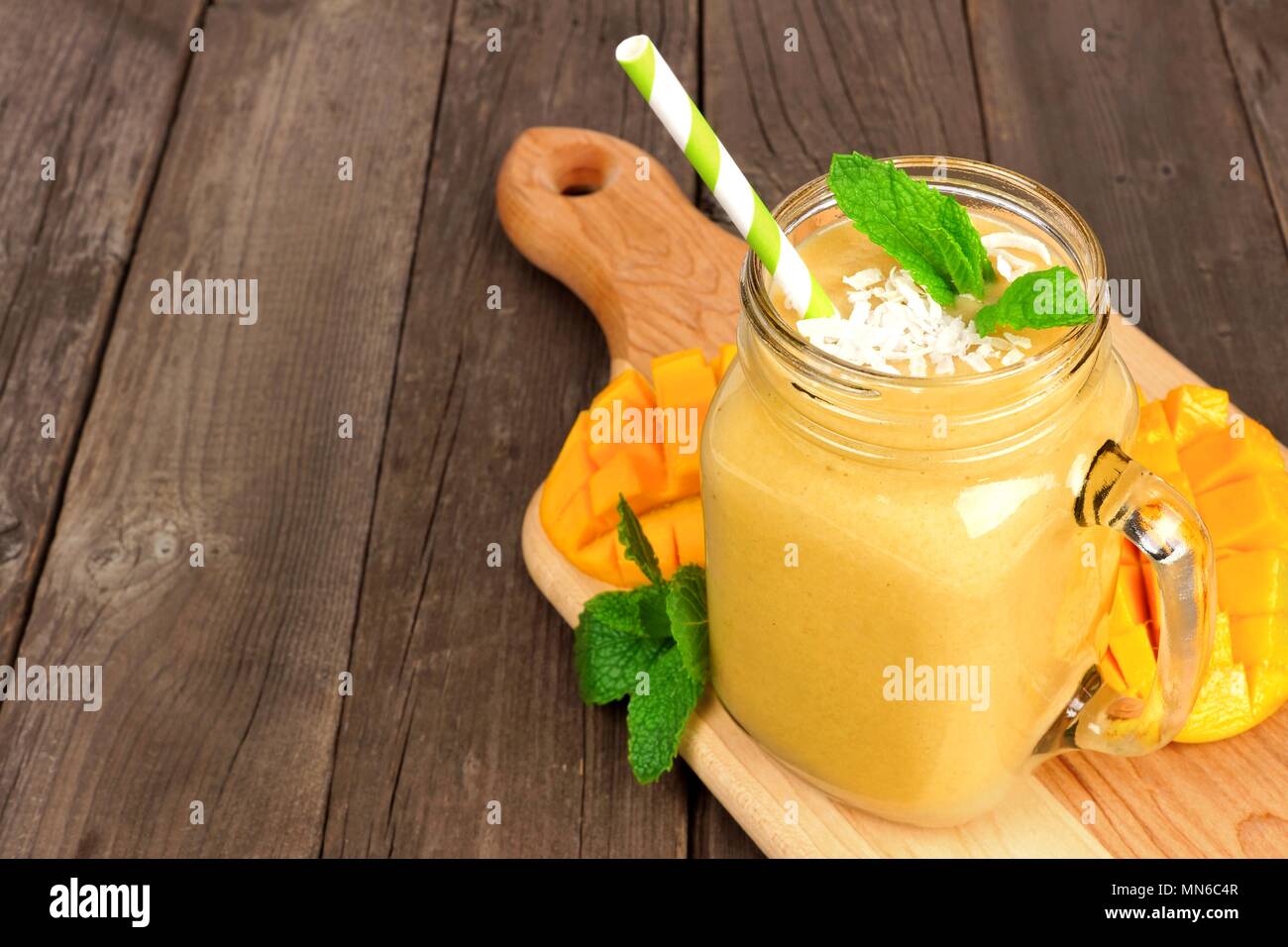 Mango coconut Smoothie in einem Marmeladenglas Glas auf paddle Board gegen ein rustikales Holz Hintergrund Stockfoto