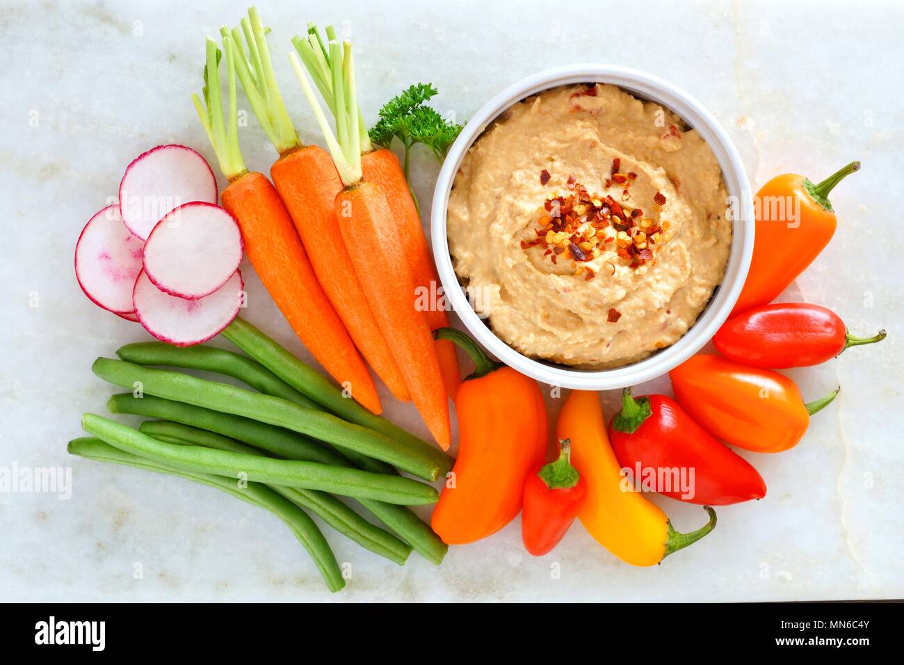 Hummus Dip mit einer Vielzahl von frischem Gemüse, oben Blick auf einen weißen Hintergrund Stockfoto