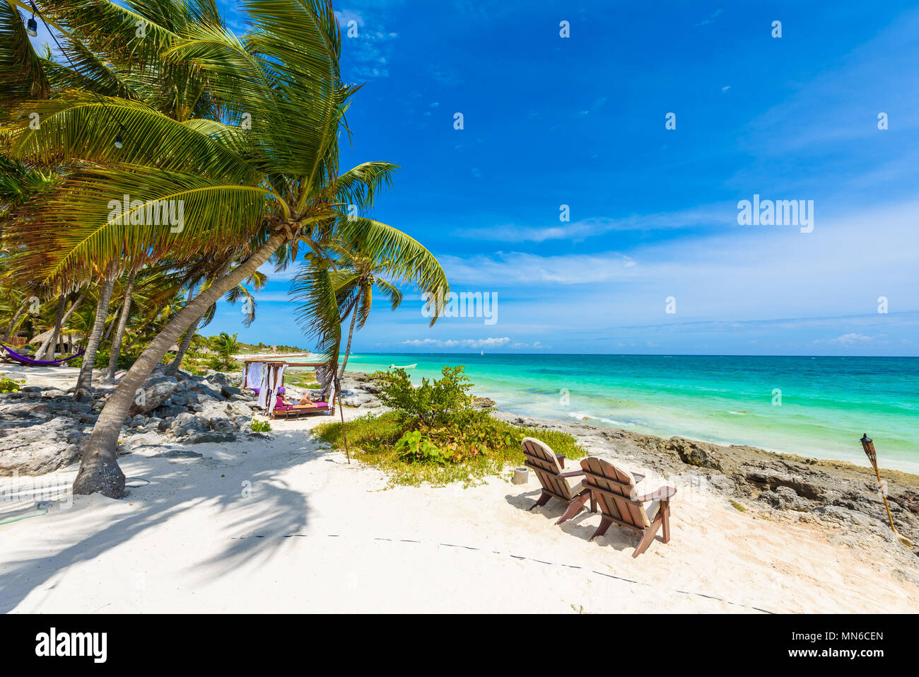 Stühle und Hängematte unter Palmen am Paradise Beach im Tropical Resort. Riviera Maya - karibische Küste in Tulum, Quintana Roo, Mexiko Stockfoto