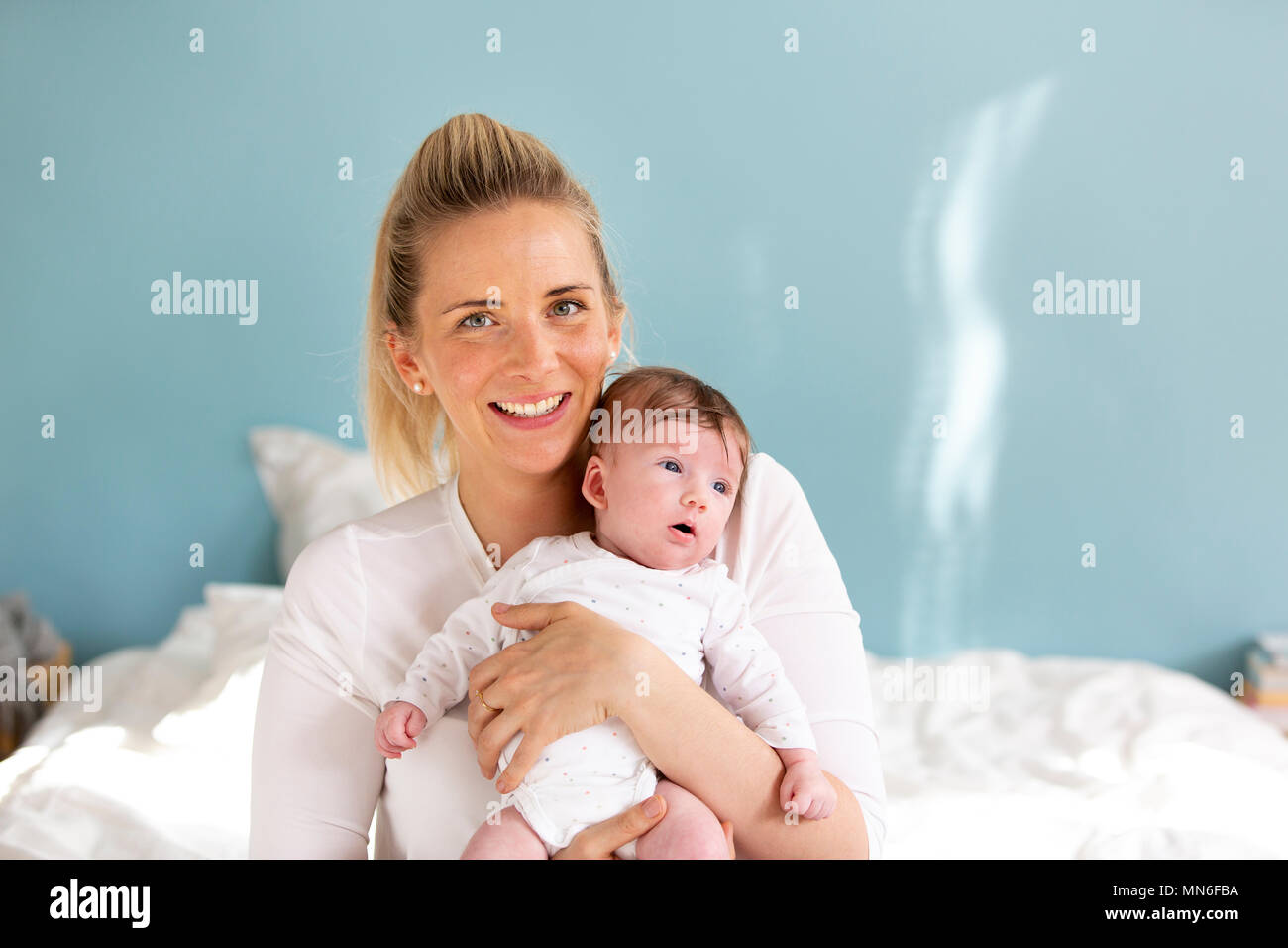 Jung, schön und blond Mutter hält ihr Baby in ihren Armen Stockfoto