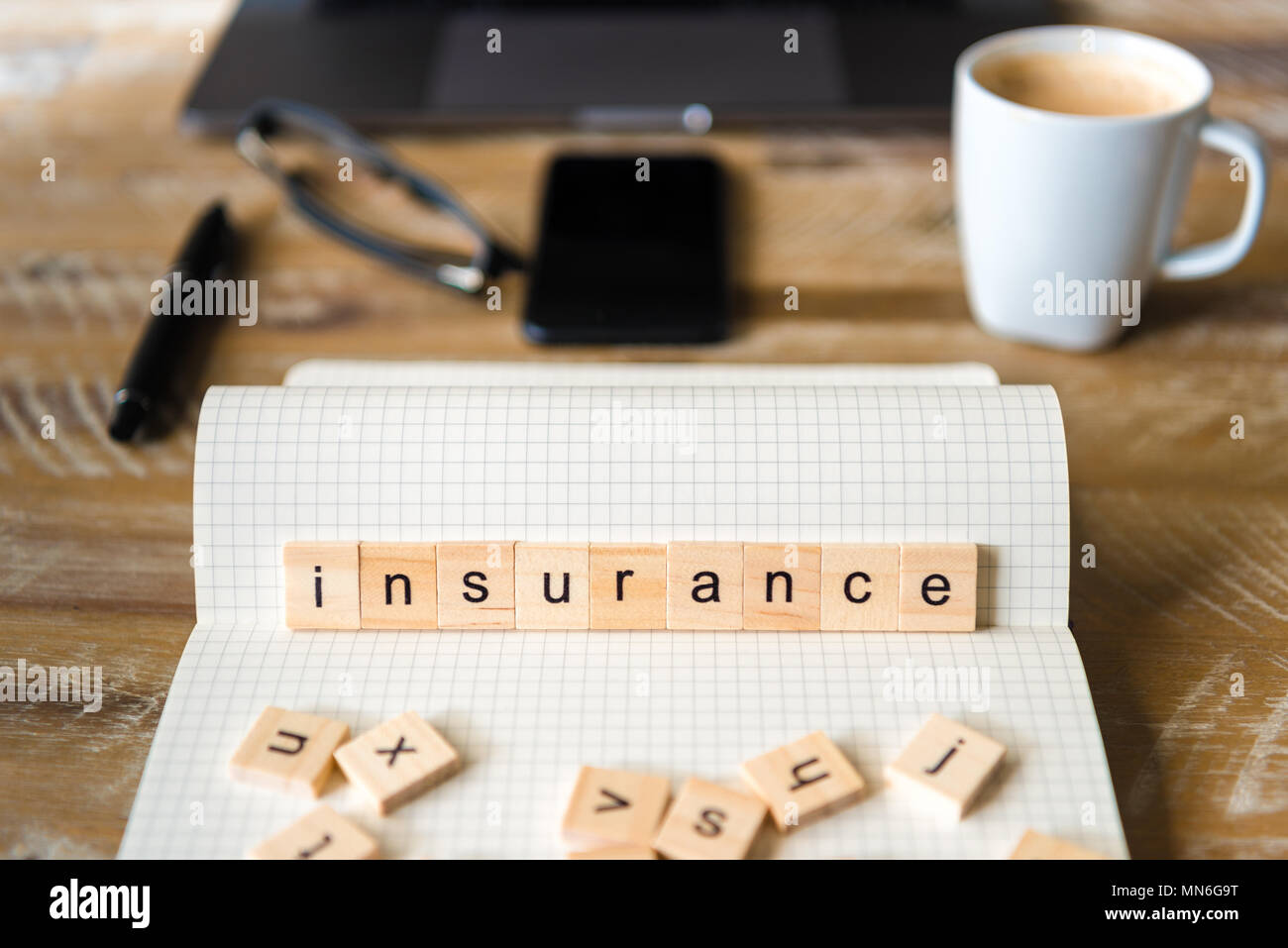 Nahaufnahme auf das Notebook um Holz Tisch Hintergrund, auf Holzblöcken mit Buchstaben, Versicherung Wort konzentrieren. Business Concept Bild. Stockfoto