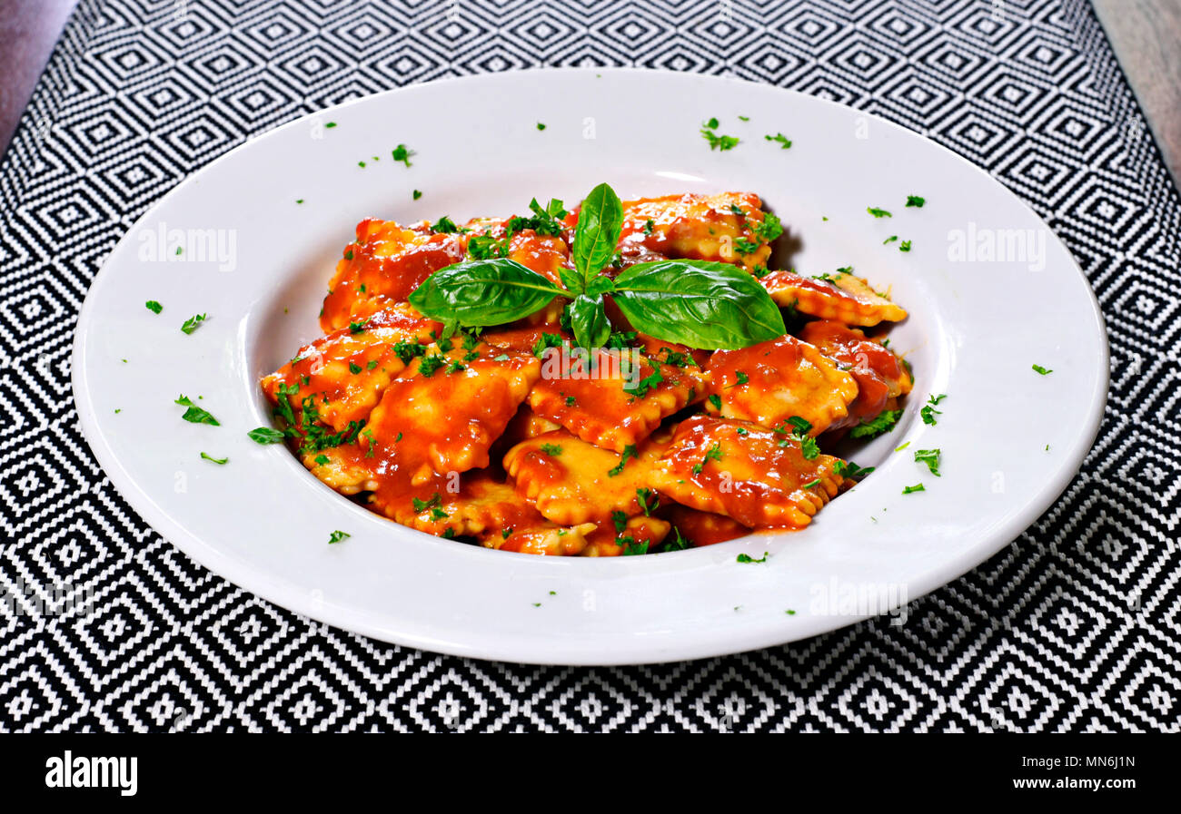 Frische ravioli Pasta mit Petersilie und Basilikum Blätter, italienische Küche. Weiße Platte und Holztisch, Pasta. Stockfoto