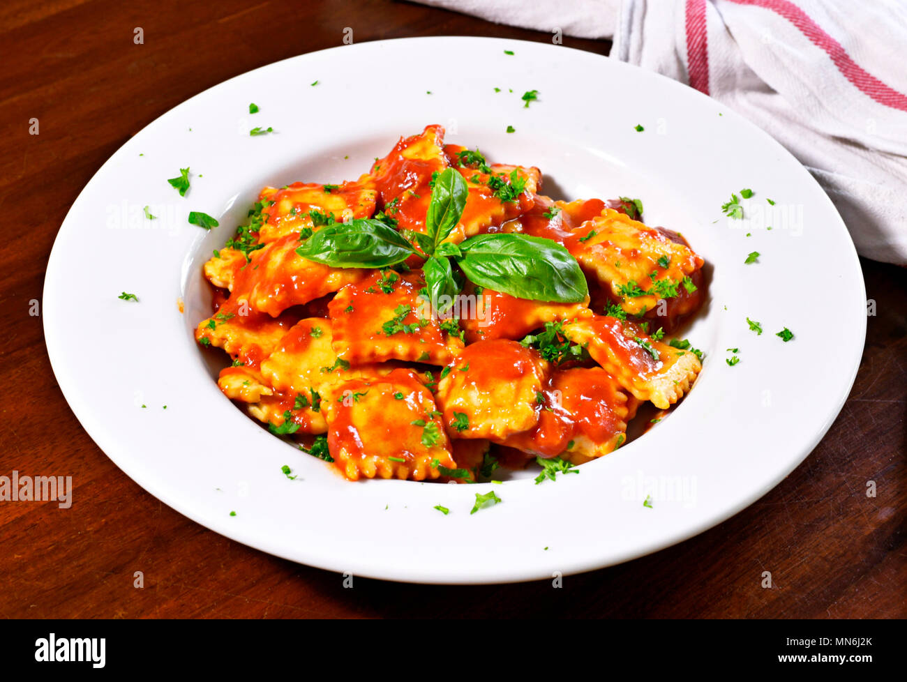 Frische ravioli Pasta mit Petersilie und Basilikum Blätter, italienische Küche. Weiße Platte und Holztisch, Pasta. Stockfoto