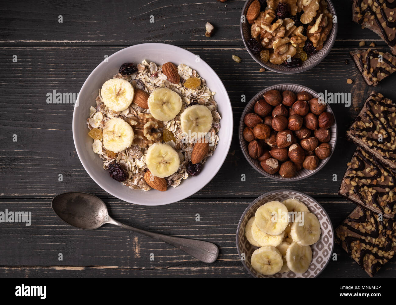 Frühstück mit Müsli in Weiß Schüssel auf Grau Schreibtisch mit Nüsse und Bananen um. Stockfoto