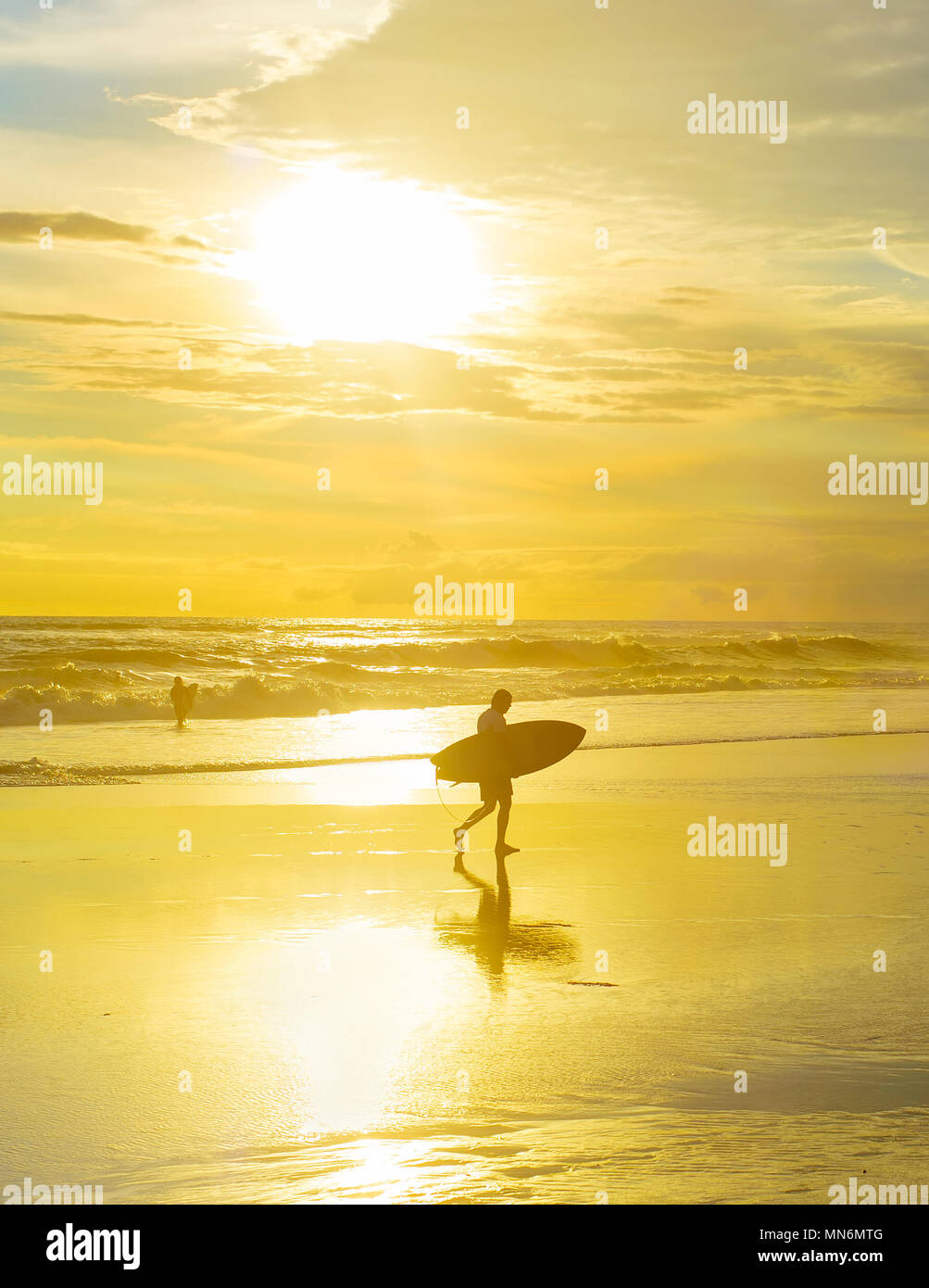 Surfer mit Surfbrett am Strand bei Sonnenuntergang zu Fuß. Insel Bali, Indonesien Stockfoto