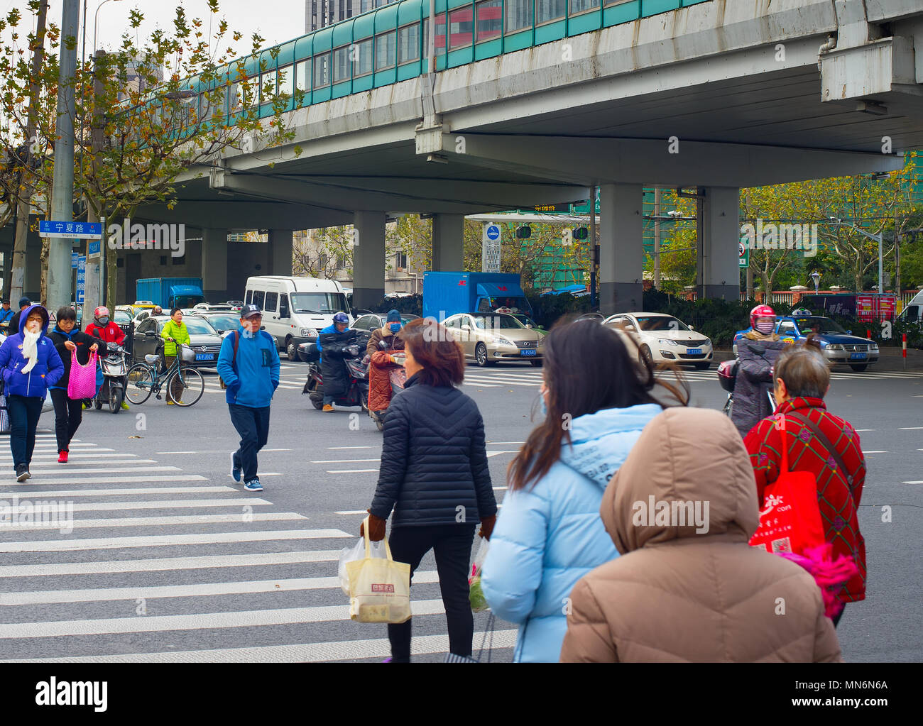 SHANGHAI, China - Dec 23, 2016: Leute, die über die Straße in der Innenstadt von Shanghai. Shanghai ist eine der am dichtesten bevölkerten Städte der Welt. Stockfoto
