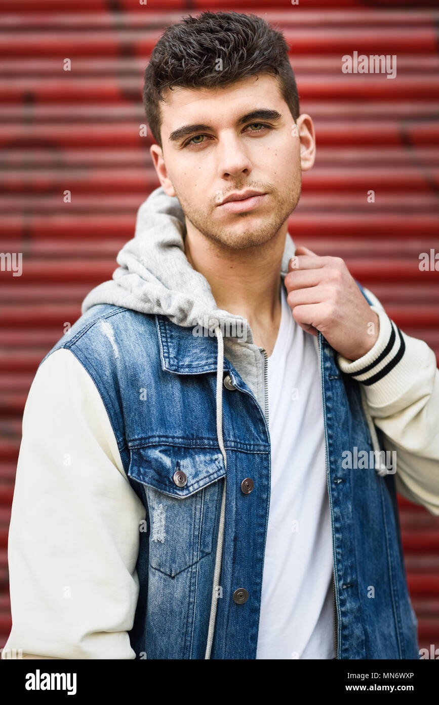 Gut aussehende junge Mann mit blauen Augen auf der Straße. Modell der Mode im städtischen Hintergrund tragen weiße T-Shirt, Jeans und blaue Jacke Stockfoto