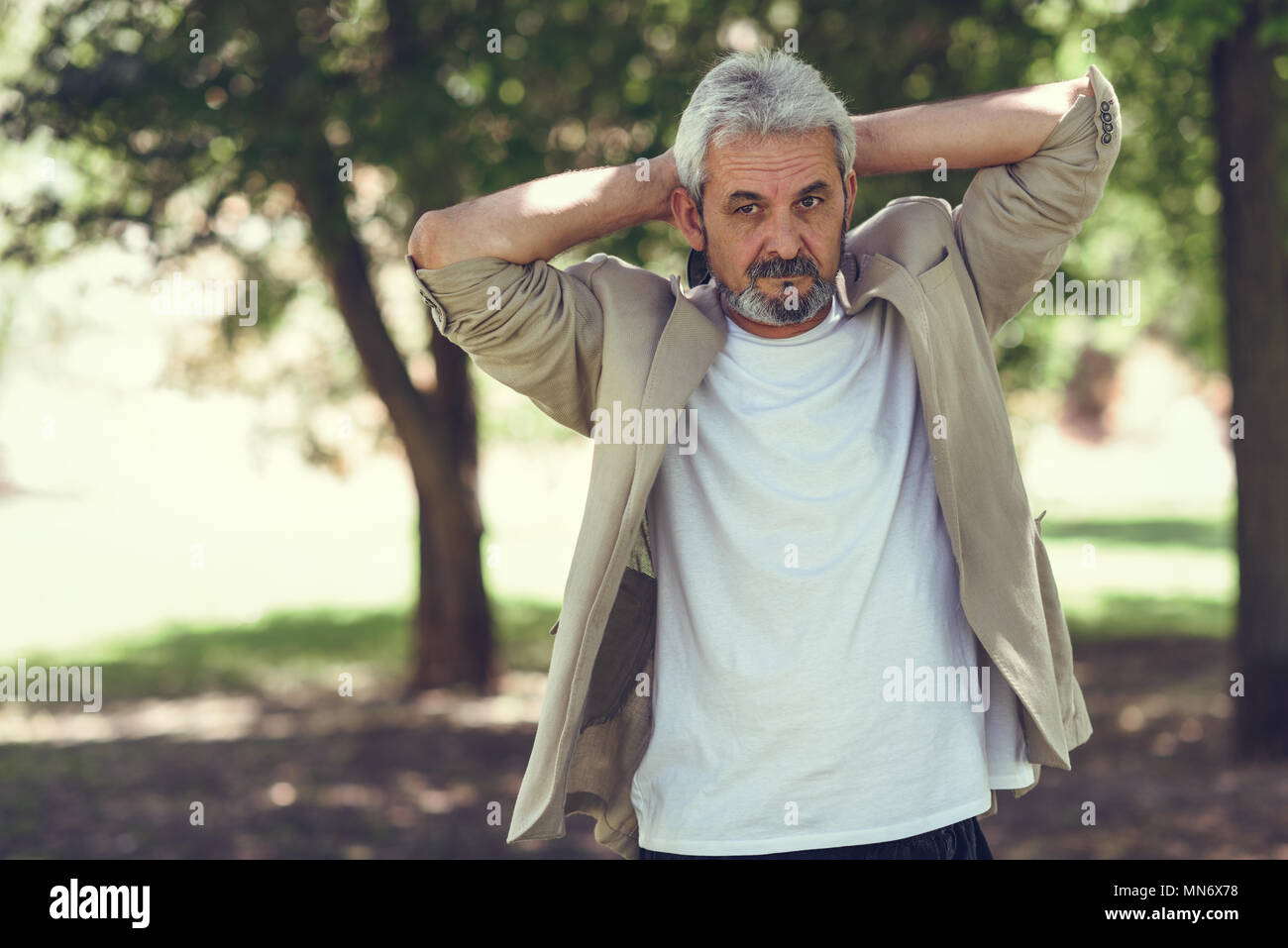 Porträt eines reifen Mannes, Modell der Mode, der in einem städtischen Park. Älterer Mann mit weissem Haar und Bart legere Kleidung. Stockfoto
