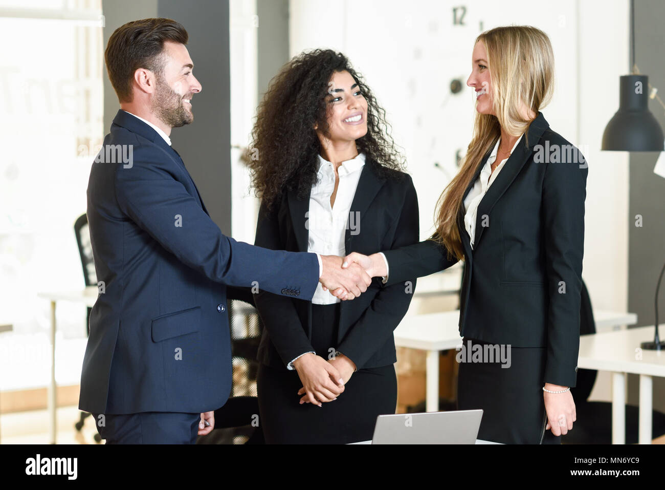 Multi-ethnischen Gruppe von drei Geschäftsleute treffen in einem modernen Büro. Kaukasische Mann und Frau tragen die Hände zu schütteln. Stockfoto
