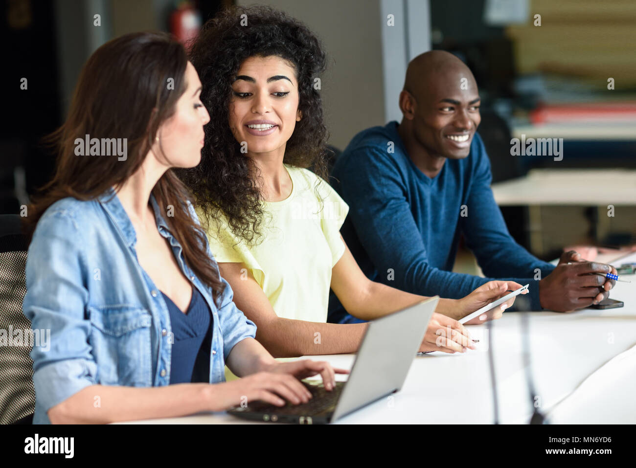 Drei junge Leute studieren mit Laptop auf weißem Schreibtisch. Schöne Mädchen und Mann arbeiten zusammen legere Kleidung. Multi-ethnischen Gruppe. Stockfoto