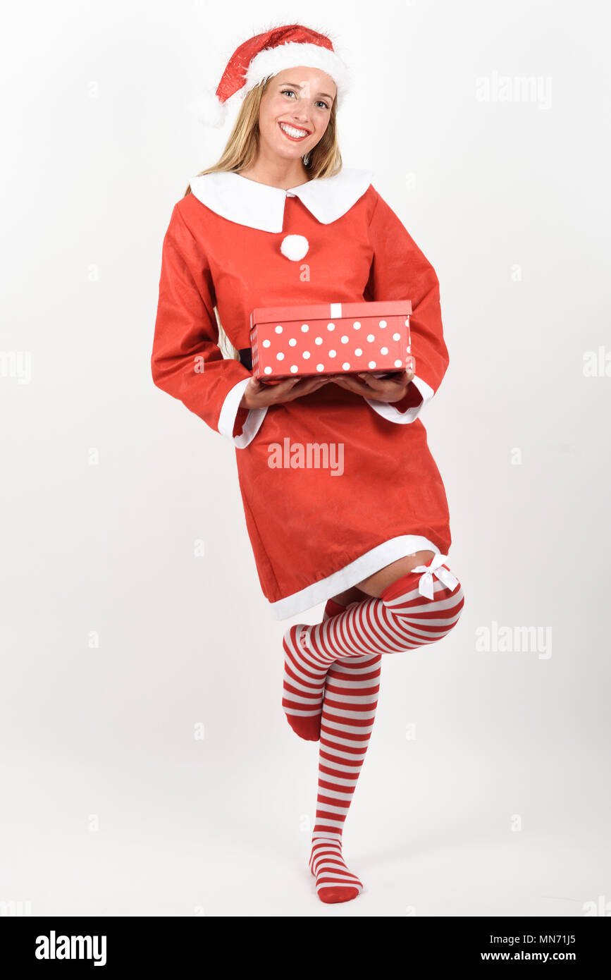 Blonde Frau in Santa Claus Kleidung lächelnd mit Geschenk in den Händen. Junge Frau mit blauen Augen das Tragen von Socken, isoliert auf weißem Stockfoto