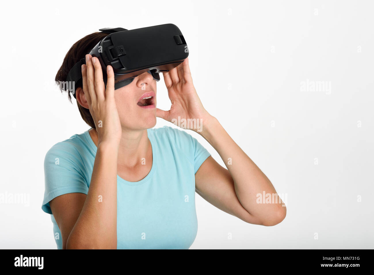 Frau Suchen im VR-Brille und gestikulierte wild mit seinen Händen. Schön überrascht weiblichen tragen virtual reality goggles Filme anschauen oder Videospiele spielen, auf weißem Hintergrund. Stockfoto