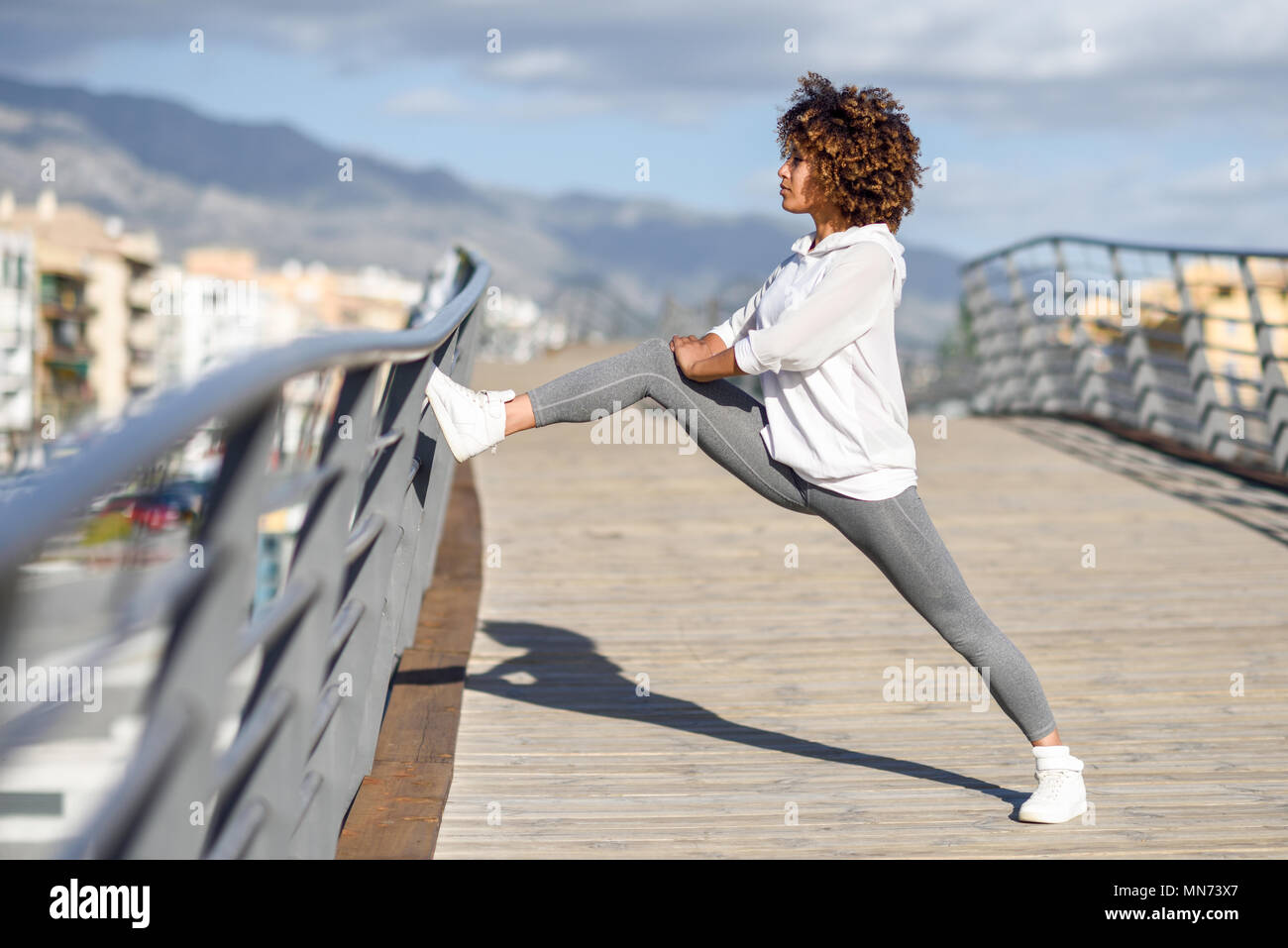 Junge schwarze Frau zu tun Stretching nach draußen. Mädchen trainieren mit City scape im Hintergrund. Afro Haar. Stockfoto