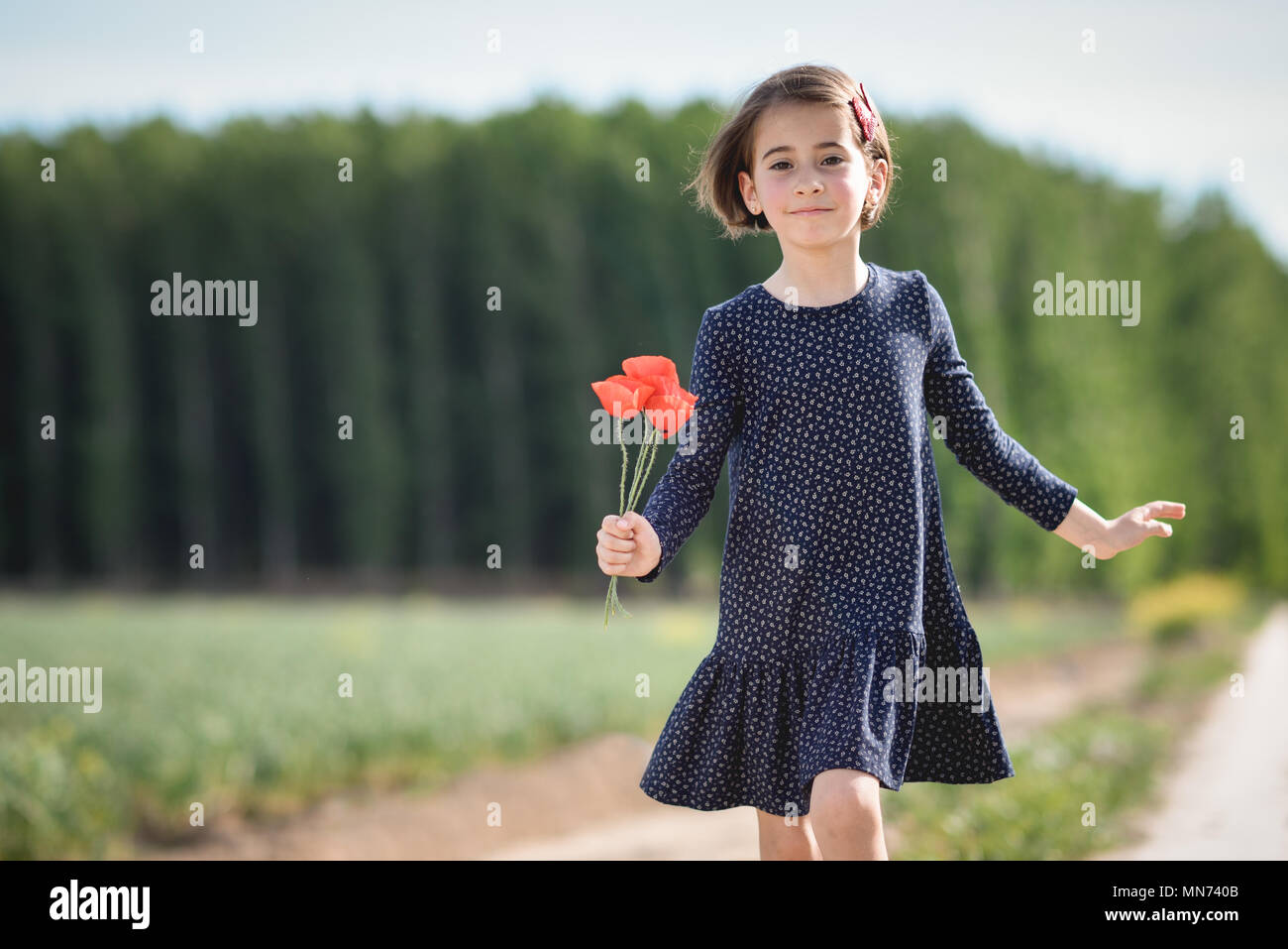 Kleines Mädchen Wandern in der Natur Feld tragen Wunderschönes Kleid mit Blumen in der Hand. Stockfoto