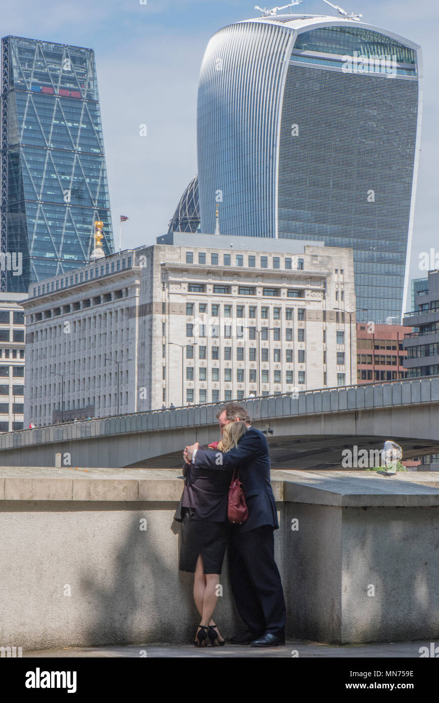 Zwei Liebende oder ein paar Kuscheln neben der Themse im Zentrum von London mit der Stadt London Financial. Bezirk im Hintergrund. Walkie Talkie. Stockfoto