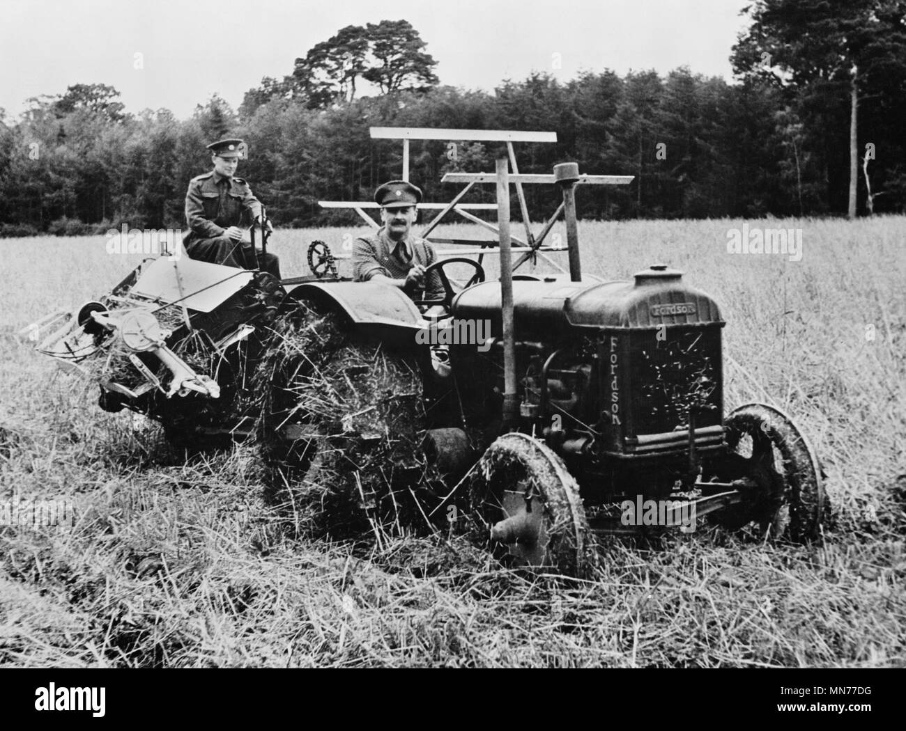 Zwei Soldaten, für landwirtschaftliche Arbeiten, Betrieb des Traktors und Harvester freigegeben Ten-Acre Feld von Hafer während der Ernte, die einfache Farm Arbeitskräftemangel während des Zweiten Weltkrieges, Nordirland, UK, US Office of War Information, April 1943 half zu schneiden Stockfoto