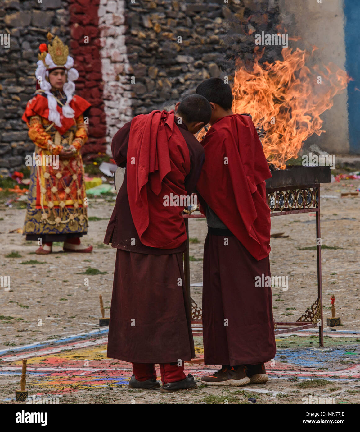 Tibetischen Mönch legt yak Butter auf dem Feuer am Jinganqumo Reinigung Festival in Dege, Sichuan, China Stockfoto