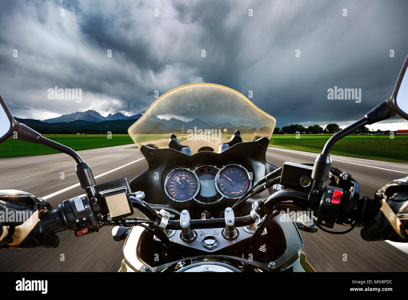 Biker auf einem Motorrad die Straße hinunter in ein Gewitter - Forggensee und Schwangau, Deutschland Bayern rast Stockfoto