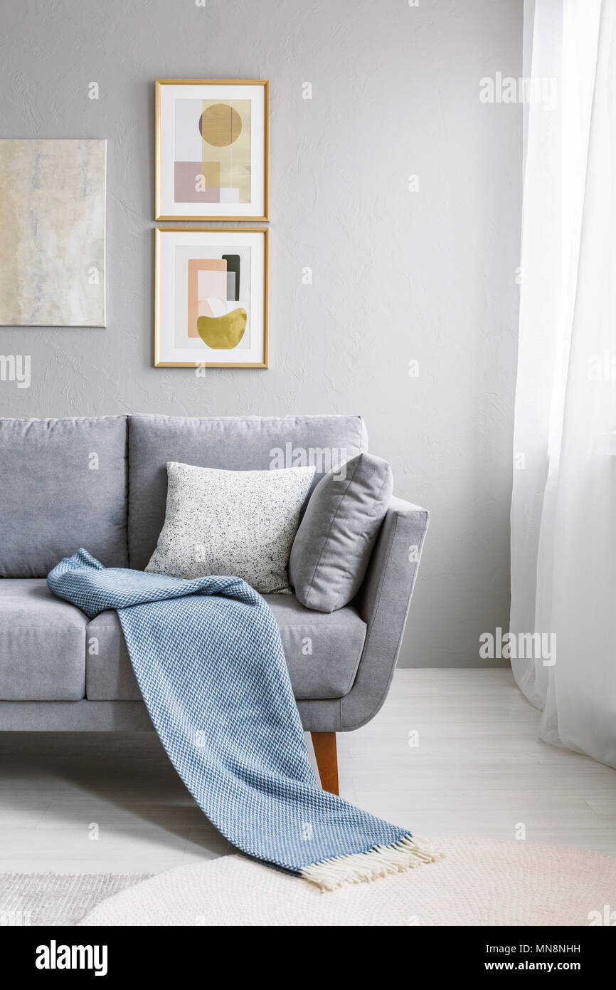 Blaue Decke auf grau Couch gegen die Wand mit gold Gemälde im Wohnzimmer. Real Photo Stockfoto