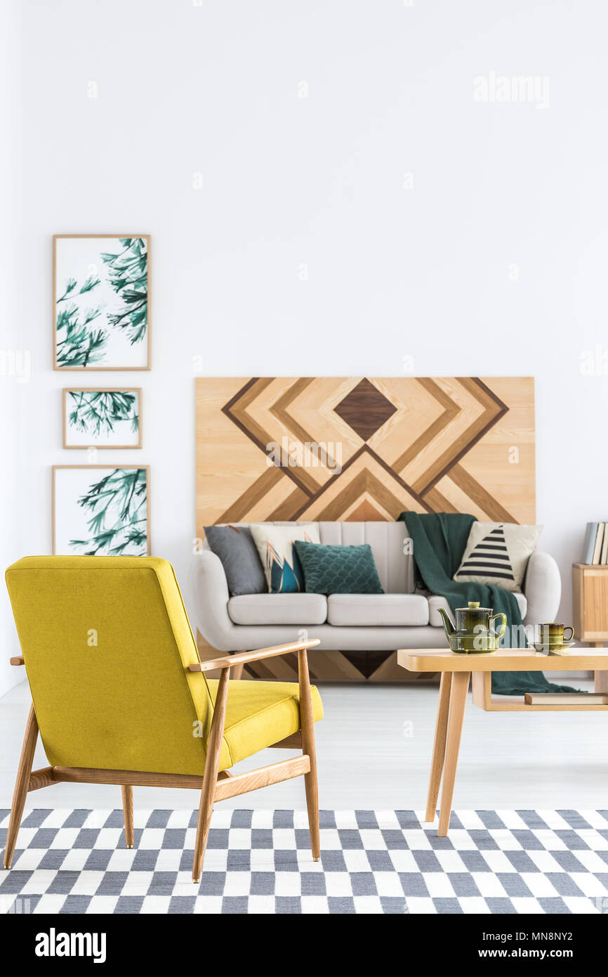 Gelbe Sessel auf gemusterten Teppich im geräumigen Wohnzimmer Innenraum mit Holz an der Wand Stockfoto