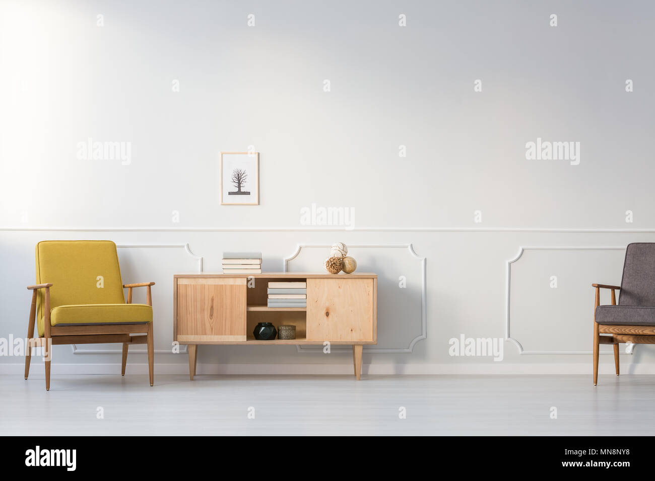 Gelb Vintage Sessel neben Holzschrank gegen weiße Wand im Wohnzimmer Innenraum Stockfoto
