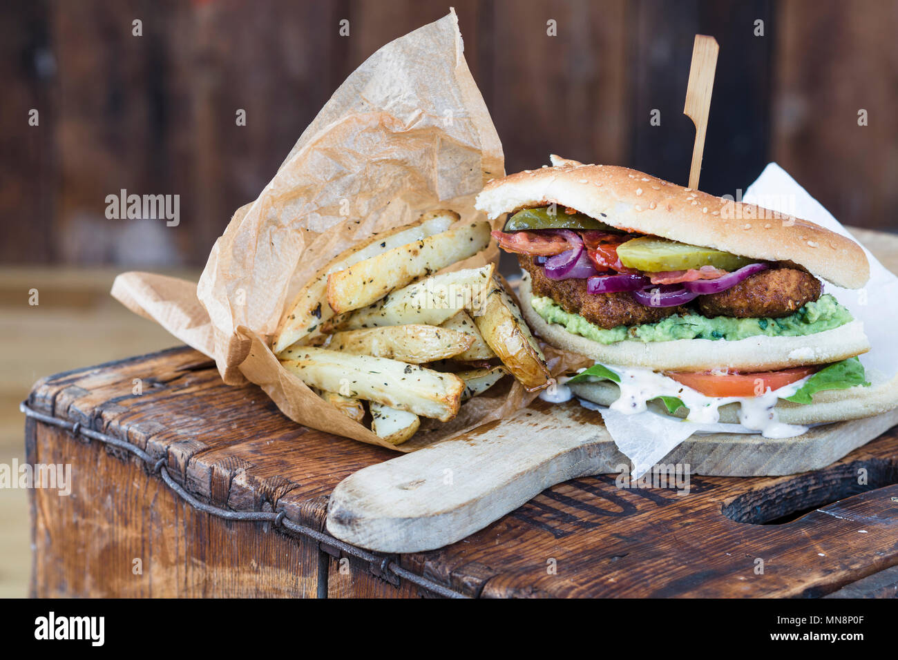 Hähnchen Schnitzel Sandwich mit Salat und hausgemachten Backofen Chips Stockfoto