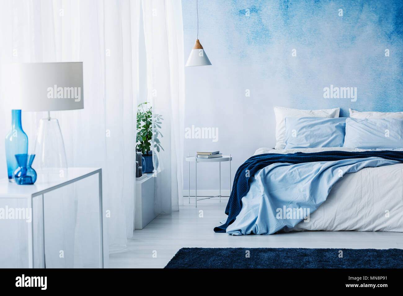 Entspannende Schlafzimmer Einrichtung mit weißen und blauen Verzierungen, Doppelbett und Tapeten Stockfoto
