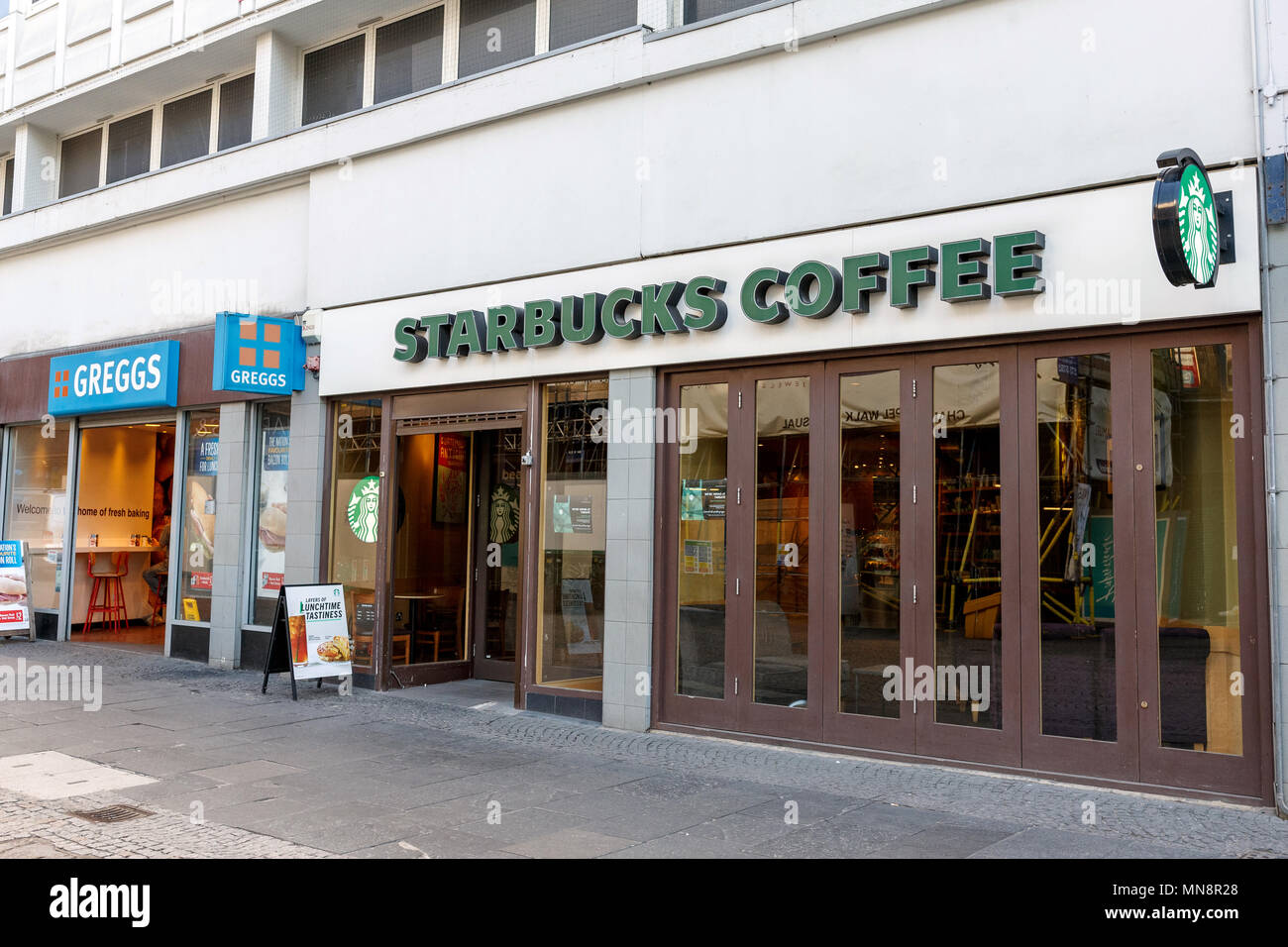 Benachbarten Branchen Greggs und Starbucks Kaffee auf einem Britischen High Street. Stockfoto