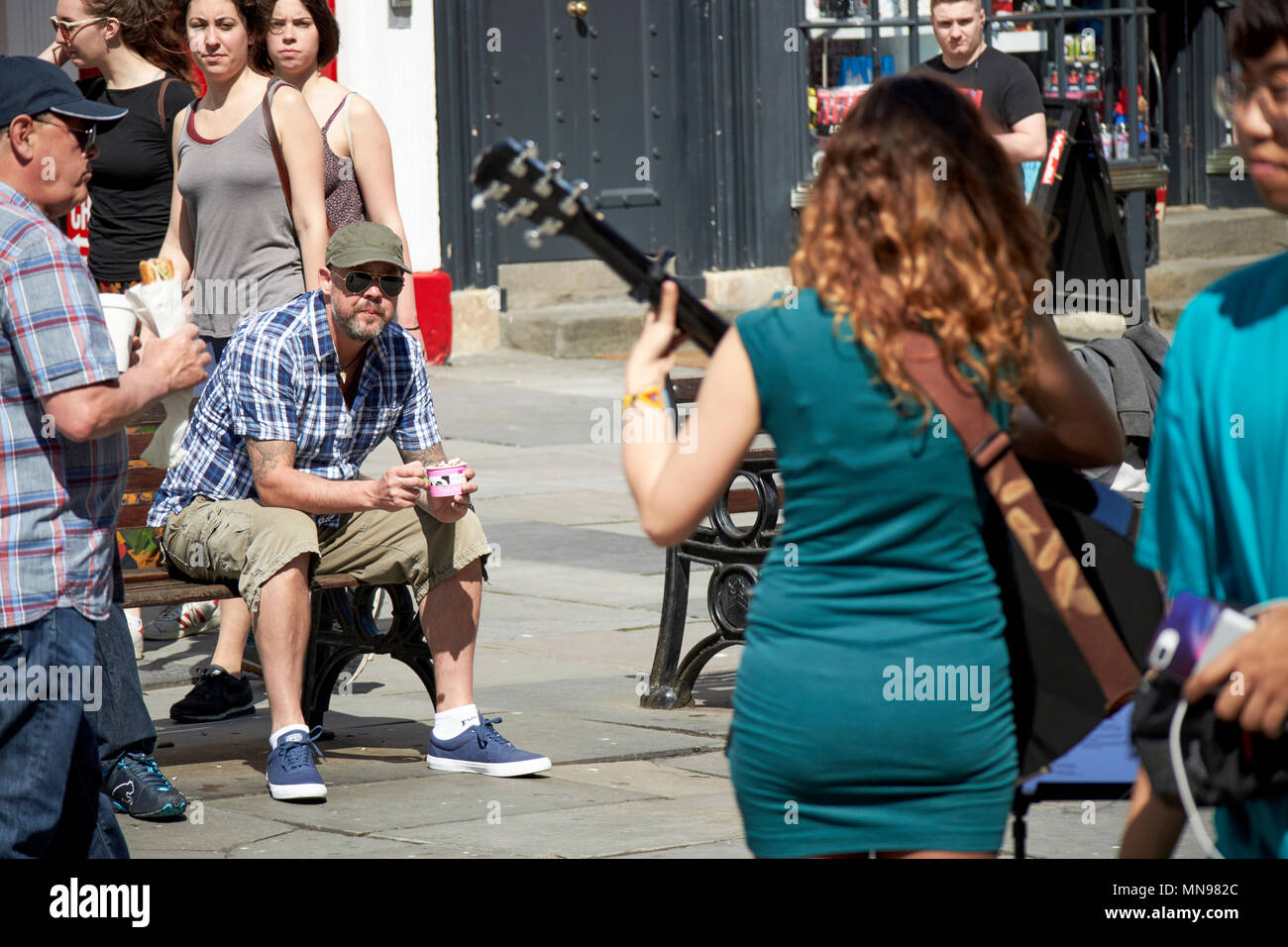 Männliche tourist sitzt und Uhren weiblichen Gaukler Spielen im Sonnenschein im Klosterhof Badewanne England Großbritannien Stockfoto