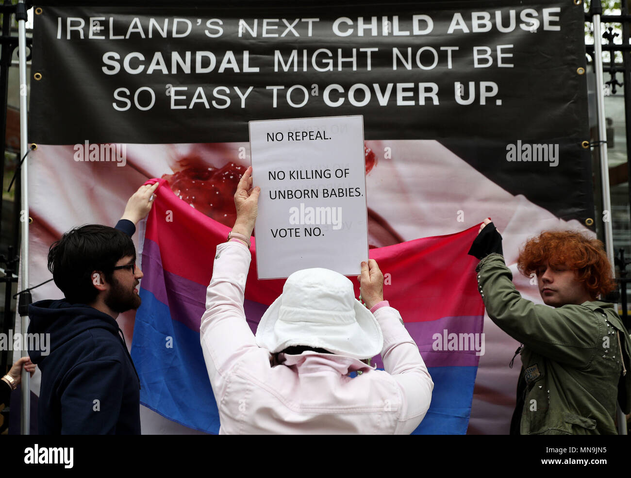Ein anti-Abtreibung Spoiler ein Zeichen oben hält als pro-choice-Aktivisten Anti-abtreibungs-Banner, die Grafiken außerhalb Leinster House, Dublin enthalten, vor dem Referendum am 8. Änderung der irischen Verfassung am 25. Mai. Stockfoto