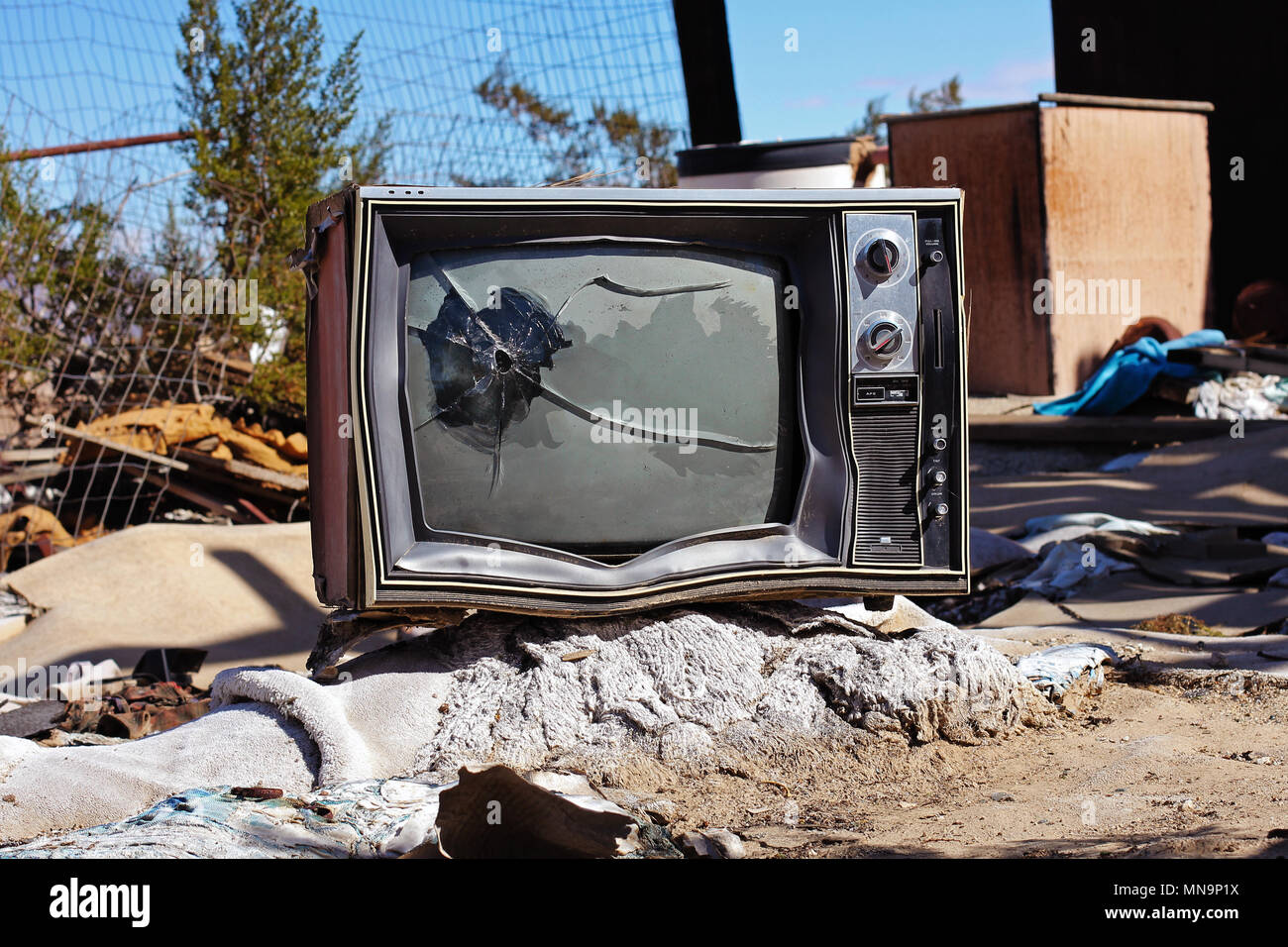 Einen alten Fernseher, durch ein Einschussloch zerbricht, in einem abfallhaufen hinter einer ruinierten verlassenes Haus, Wonder Valley, Kalifornien, USA. High Desert, Mojave. Stockfoto