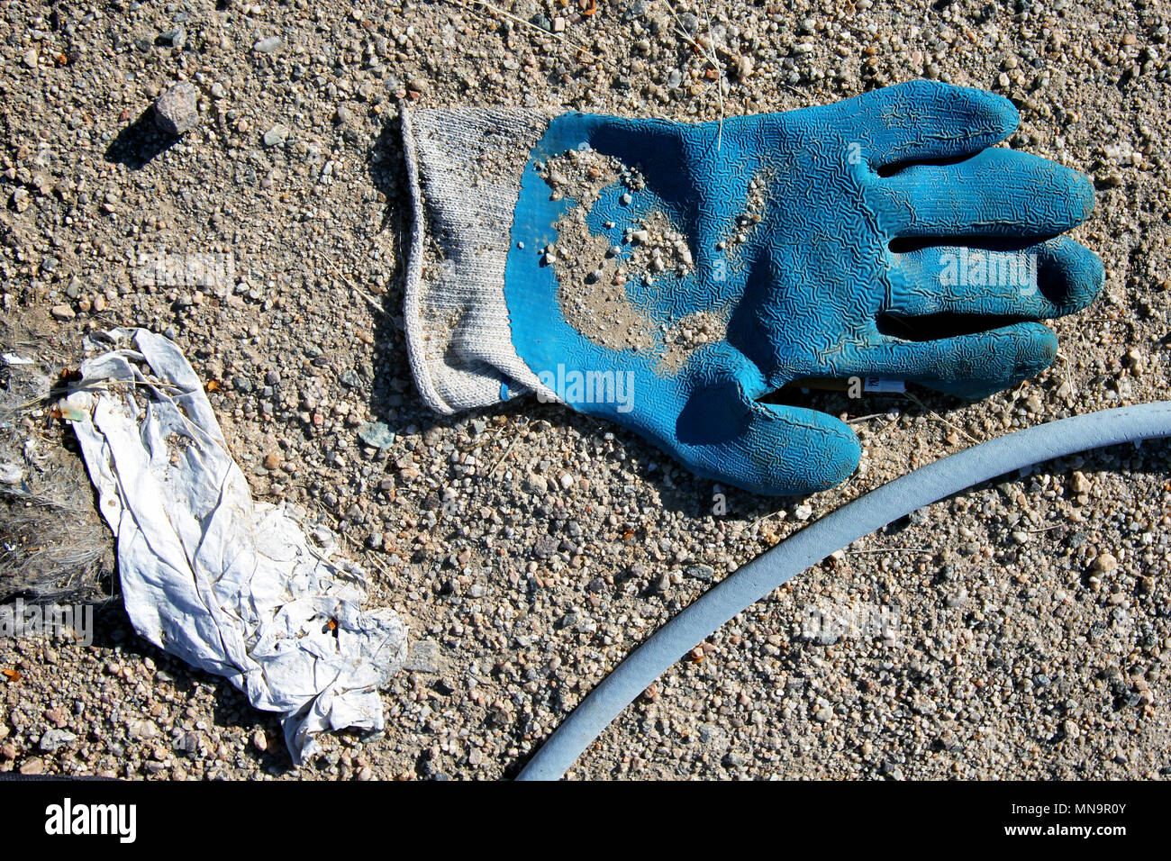 Eine weggeworfene blau Gummi schwere Handschuh liegt in den kiesigen Straße Schmutz in der hohen Wüste, die in der kalifornischen Mojave-Wüste, Wonder Valley, USA Stockfoto