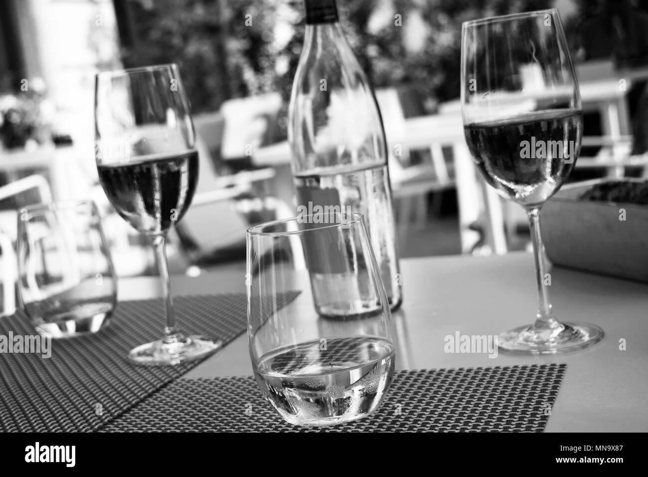 Tabelle Einstellung mit kristallklarem Wasser und Wein Gläser und eine Flasche Wasser in Schwarz und Weiß. Stockfoto
