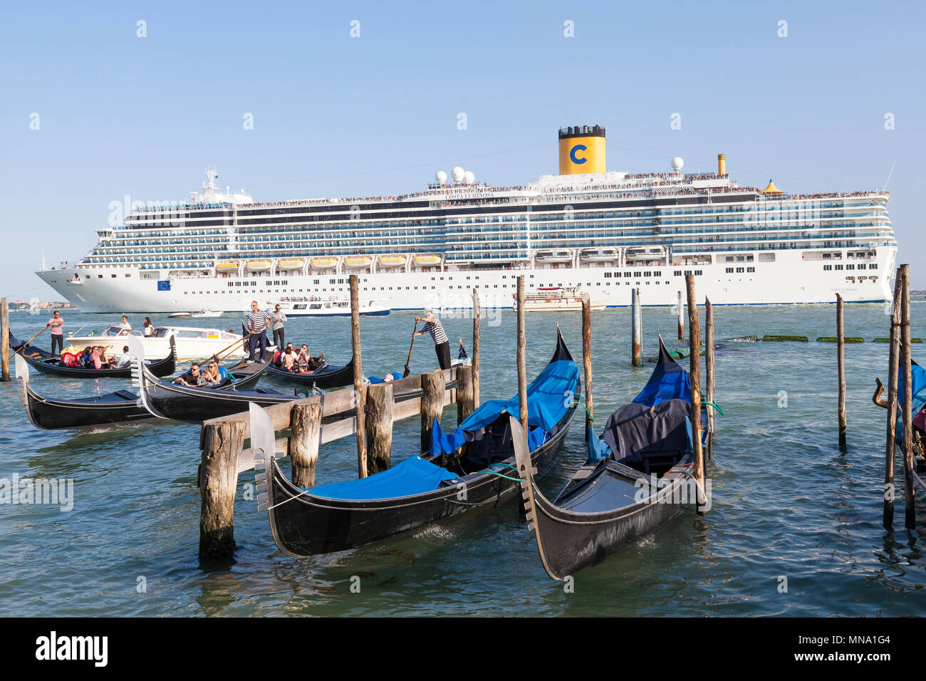Gegenüberstellung von kleinen Gondeln und Vaporetto und dem riesigen Coasta Luminosa Passagierschiff in St Marks Becken bei Sonnenuntergang, Venedig, Venetien, Italien Stockfoto