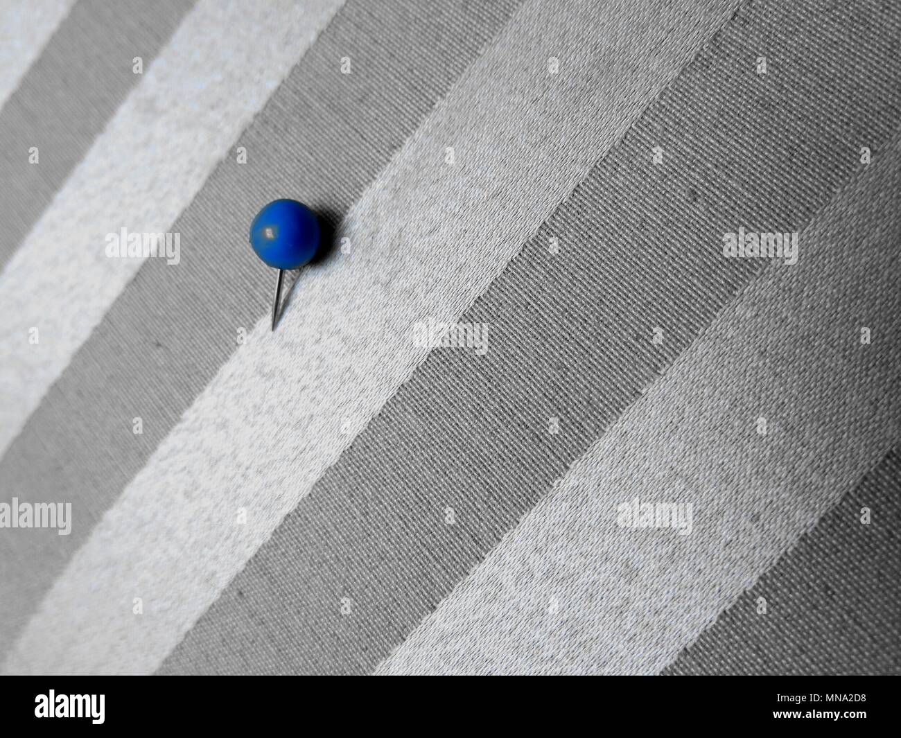 Blue Pin auf gemusterten Stoff. Konzept: Minimalismus in der Fotografie. Stockfoto