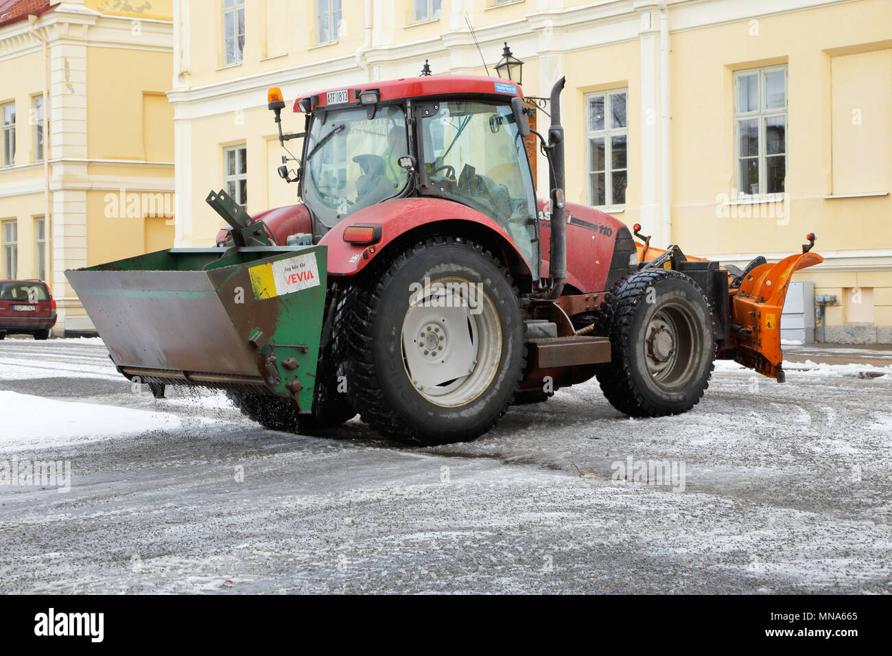Strangnas, Schweden - 21. Februar 2016: ein Traktor in die Arbeit Schleifen der Platz mit Kies aus dem Behälter an der Rückseite angebracht. Stockfoto