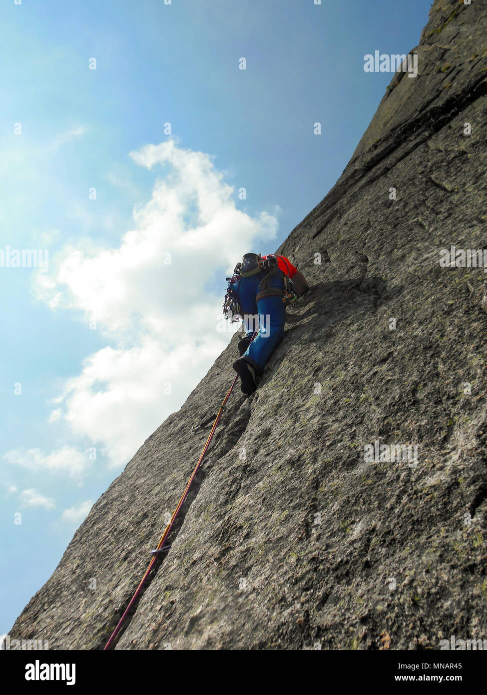 Kletterer in hellen Farben gekleidet auf einem steilen Granit Klettersteig in den Alpen Stockfoto