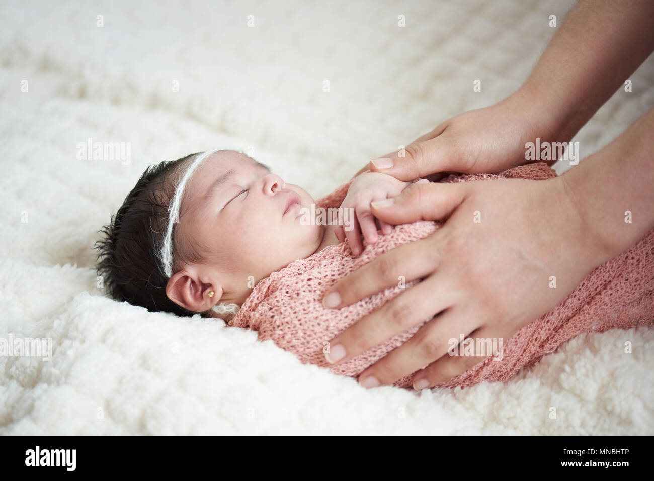 Mama kümmert sich um New Born Baby auf weichen weißen Decke Hintergrund Stockfoto