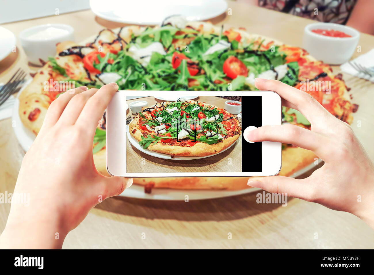 Das zusammengesetzte Bild, pizza Fotos auf einem Smartphone - Woman's Hände, die Mobiltelefon und berühren Auslöser auf dem Bildschirm. Stockfoto